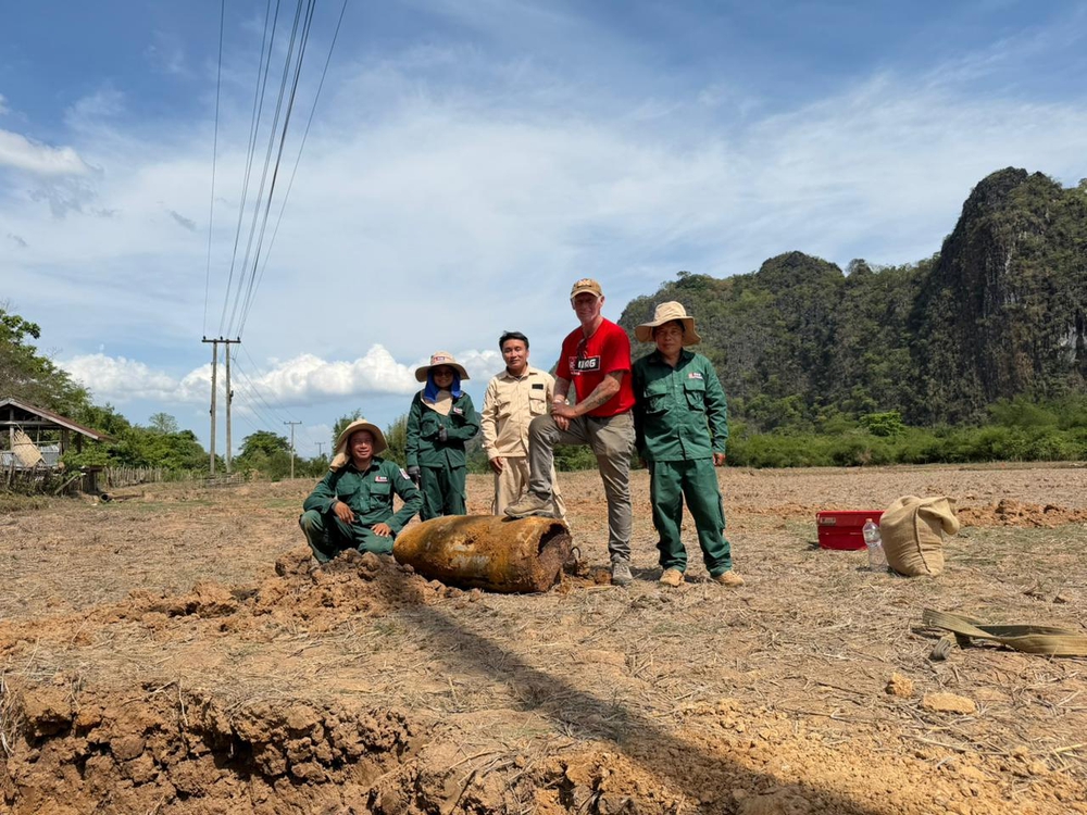 MAG staff smiling with large bomb